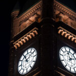 The clock tower of Minneapolis City Hall glows at night, its illuminated faces visible across downtown. The landmark’s Romanesque architecture remains a defining feature of the city’s skyline.