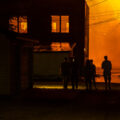 People walking down an alley as fires burn across the street during the 2nd day of protests in Minneapolis following the death of George Floyd.