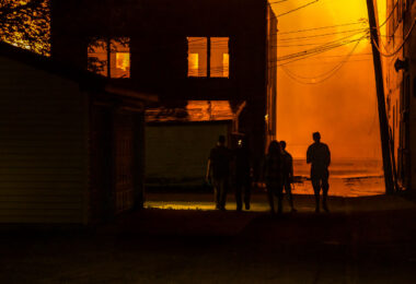 People walking down an alley as fires burn across the street during the 2nd day of protests in Minneapolis following the death of George Floyd.