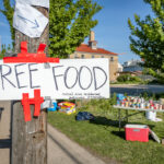 Sign that reads "FREE FOOD Central area neighborhood development organization". Food stands popped up after grocery stores were burned and other store damage following nights of riots in Minneapolis after the death of George Floyd.