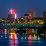 Downtown Minneapolis as seen from Boom Island in May 2020. Gold Medal Flour and Northstar Blankets neon signs visible across the Mississippi River.