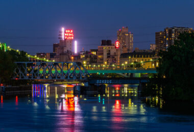 Downtown Minneapolis as seen from Boom Island in May 2020. Gold Medal Flour and Northstar Blankets neon signs visible across the Mississippi River.