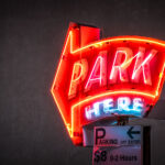 A neon sign in downtown Minneapolis that reads "PARK HERE".