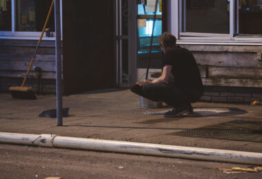 A man cleans glass up off the sidewalk from broken windows during the Minneapolis Uprising on May 30, 2020.
