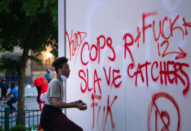 A man writes on a Target sign across from the Minneapolis police third precinct.