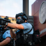 A Minneapolis Police officer aiming his less lethal weapon outside the Minneapolis Police 3rd Precinct on the second day of protests.