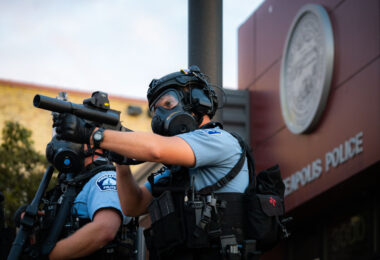 A Minneapolis Police officer aiming his less lethal weapon outside the Minneapolis Police 3rd Precinct on the second day of protests.