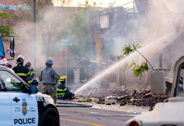 Minnesota National Guard and Minneapolis Police look on as the Minneapolis Fire Department fight fires on Lake Street after another night of protests and riots in Minneapolis after the death of George Floyd.