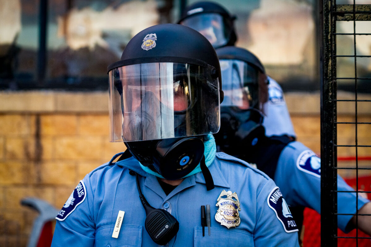 A Minneapolis police officer stands outside the third precinct on the second day of protests following the death of George Floyd.