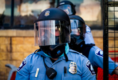 A Minneapolis police officer stands outside the third precinct on the second day of protests following the death of George Floyd.