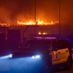 A Minneapolis Police squad car while buildings burn behind it during the 2nd day of protests in Minneapolis following the death of George Floyd.