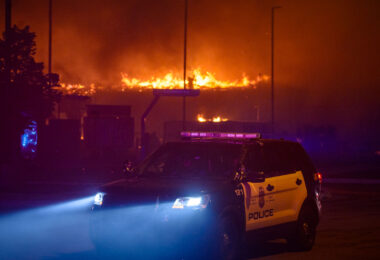 A Minneapolis Police squad car while buildings burn behind it during the 2nd day of protests in Minneapolis following the death of George Floyd.