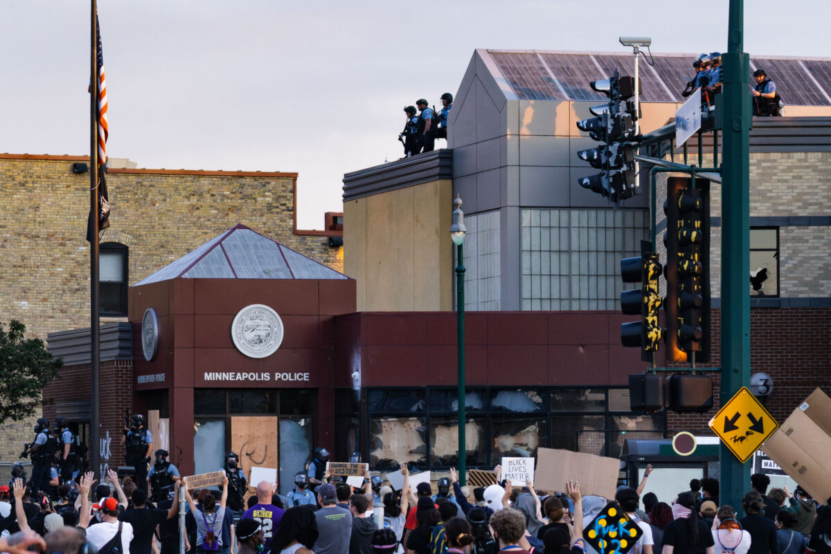 Protesters outside Minneapolis Police 3rd Precinct on Lake Street as officers stand on the roof.