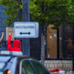 Protesters hold their fists up outside the Minneapolis Police 3rd Precinct police station. Police officers behind broken glass on day 1 of protests after the death of George Floyd the night before.