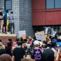 Protesters with signs outside the back door of the Minneapolis police third precinct.