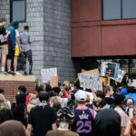 Protesters with signs outside the back door of the Minneapolis police third precinct.