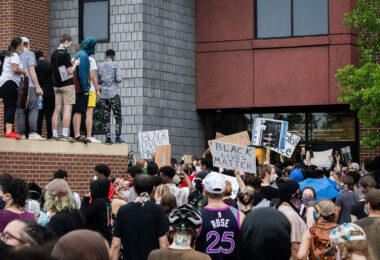 Protesters with signs outside the back door of the Minneapolis police third precinct.