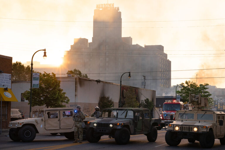 Sun rises behind Midtown Minneapolis 1 The Minnesota National Guard guards the Minneapolis Fire Department as they work to put out fires following nights of protests in Minneapolis following the death of George Floyd.