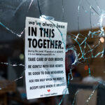 Broken storefront window during the riots on the 2nd day of protests in Minneapolis following the death of George Floyd. Sign hanging in the window reading "We've always been in this together. During the covid 19 pandemic & ALWAYS, it is our shared responsibility to- Take care of our bodies. Be gentle with our hearts. Be good to our neighbors. Ask for help when we need it. Accept love when it arrives. Our impact matters.