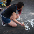 A woman paints Black Lives Matter at the George Floyd memorial at 38th St and Chicago Ave on May 31, 2020.