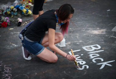 A woman paints Black Lives Matter at the George Floyd memorial at 38th St and Chicago Ave on May 31, 2020.