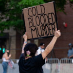 A protester holds up a sign reading "Cold Blooded Murder" outside the Minneapolis police third precinct.