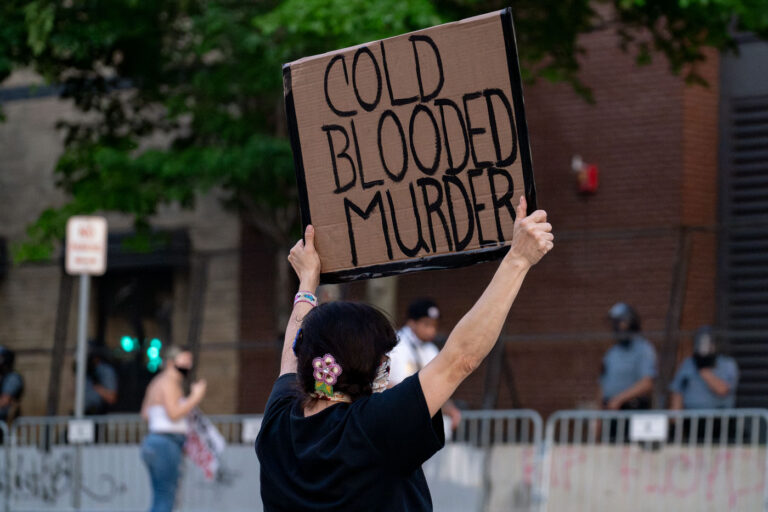 Minneapolis Police Third Precinct 3 A protester holds up a sign reading "Cold Blooded Murder" outside the Minneapolis police third precinct.