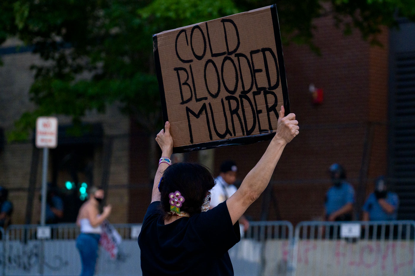 Woman holds up sign reading cold blooded murder
