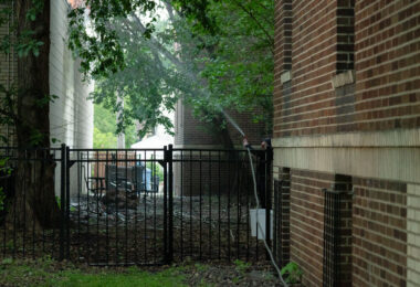A couple use a hose to battle a fire at an O'Reilly Auto Parts store next to their apartment building on May 30, 2020.