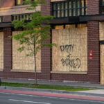A cyclist bikes down Hennepin Avenue in Uptown Minneapolis past a boarded up Walgreens Pharmacy. Boards were placed after unrest in Minneapolis over the killing of George Floyd on May 25th, 2020.