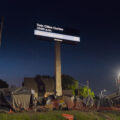 Billboard reading "Twin Cities Curfew. Please stay home" with a homeless camp below. Shot during the 2020 Minneapolis unrest over the May 25th death of George Floyd.