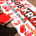 Protesters dip their hands in red paint to leave hand prints on a protest banner that reads “Bob Kroll has blood on his hands”. The protest outside of the Minneapolis police union headquarters where Bob Kroll was the union head for many years.