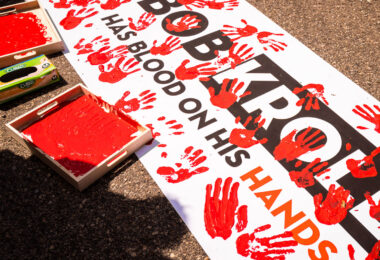 Protesters dip their hands in red paint to leave hand prints on a protest banner that reads “Bob Kroll has blood on his hands”. The protest outside of the Minneapolis police union headquarters where Bob Kroll was the union head for many years.