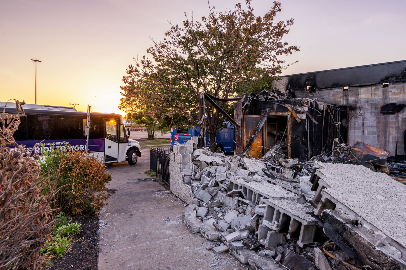 Bus stops outsider rubble of burned out building