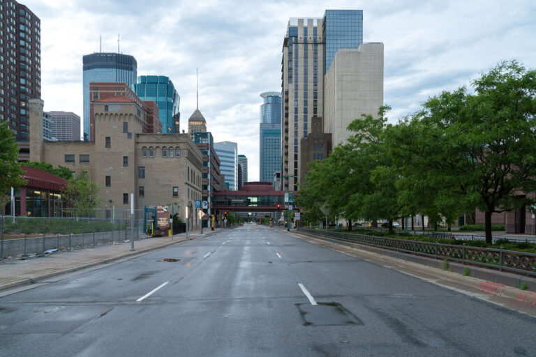 Empty Street Near Minneapolis Convention Center, Post-Unrest 3 A deserted street in downtown Minneapolis near the Minneapolis Convention Center on May 29, 2020. The city experienced widespread protests and civil unrest following the death of George Floyd on May 25, 2020. The Minneapolis Convention Center, a significant venue for large-scale events, is visible in the background alongside other downtown structures, including the historic Foshay Tower. This quiet thoroughfare reflects the immediate aftermath of the events that led to temporary closures and reduced activity in the city's central business district.