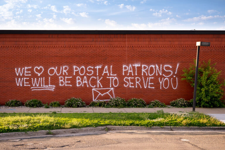 We love our postal patrons! 1 Graffiti reading “We love our postal patrons! We will be back to serve you”. The post office was destroyed in the days following George Floyd May 2020 murder.