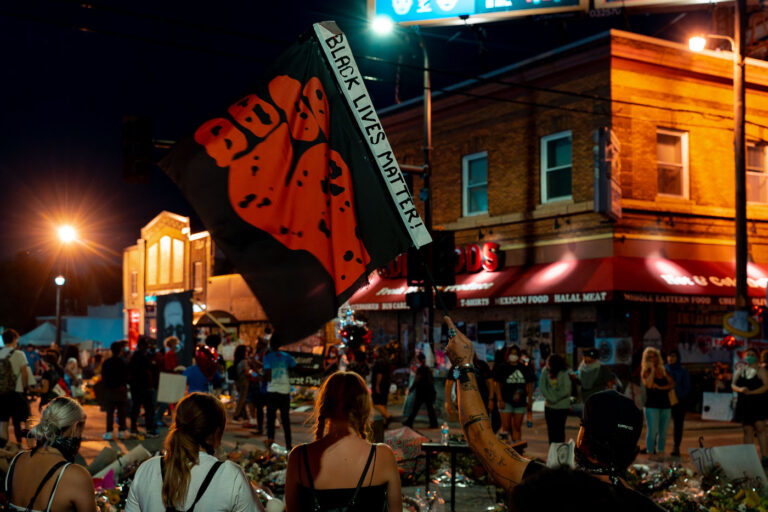 Black Lives Matter flag at George Floyd Square 3 Protester holds up a “Black Lives Matter” flag at 38th St and Chicago Ave where George Floyd died on May 28th, 2020.