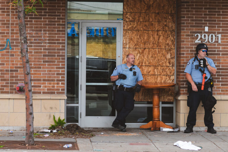 Police officers guard abandoned hotel 2 Minneapolis Police stand outside an entrance to the Sheraton Hotel in Midtown Minneapolis while clearing and boarding it.