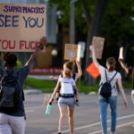 Protester holds up a sign reading “White supremacists We See You… you fucks” as they march down Park Avenue into downtown Minneapolis.