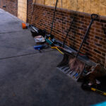 Brooms and shovels on the side of a building for community cleanup of damaged buildings during civil unrest in Minneapolis.
