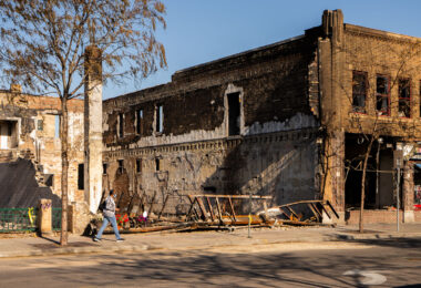 Woman walking in front of the remains of Chicago Furniture. The store was burned during unrest in Minneapolis following the May 25th, 2020 death of George Floyd.