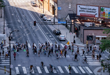 Protesters march around the Federal Courthouse in downtown Minneapolis. Protesters gathered on July 23rd, 2020 to protest federal officers being deployed to cities around the country. Billboard above that reads “Uptown reels after gunfire, bloodshed”.
