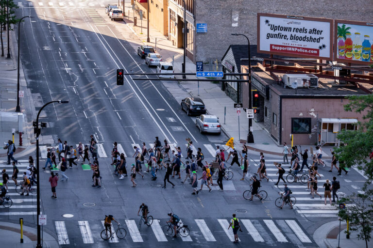 Uptown Reels after gunfire, bloodshed 2 Protesters march around the Federal Courthouse in downtown Minneapolis. Protesters gathered on July 23rd, 2020 to protest federal officers being deployed to cities around the country. Billboard above that reads “Uptown reels after gunfire, bloodshed”.