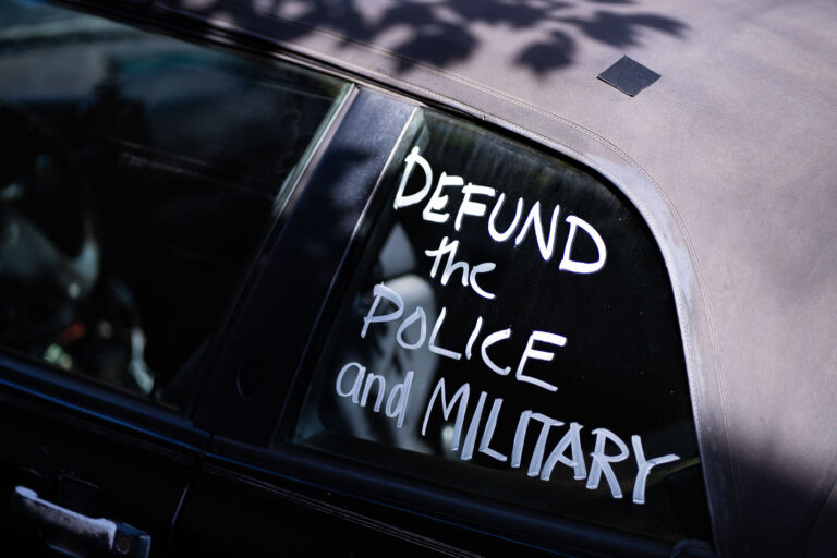 Defund the police and military 4 A car with “Defund the police and military” written on a window.