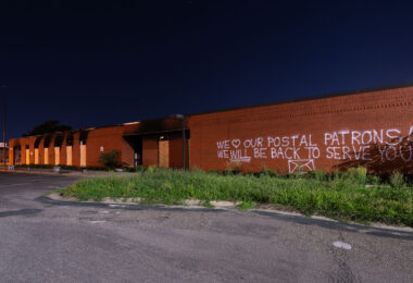 Graffiti on the damaged Lake Street Station post office. 

“We love our postal patrons! We WILL be back to serve you!”