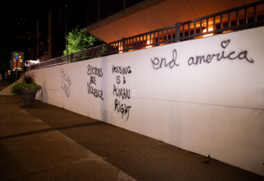 Stolen Land, Housing is a human right, end America written on the side of the Hennepin County Medical Center.