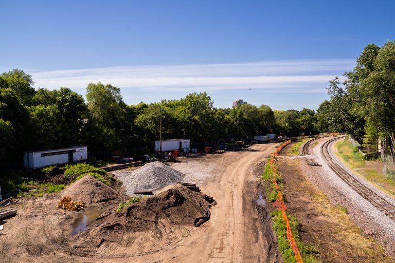 Southwest LRT construction site along Kenilworth Trail in Minneapolis with excavated earth and railroad tracks.