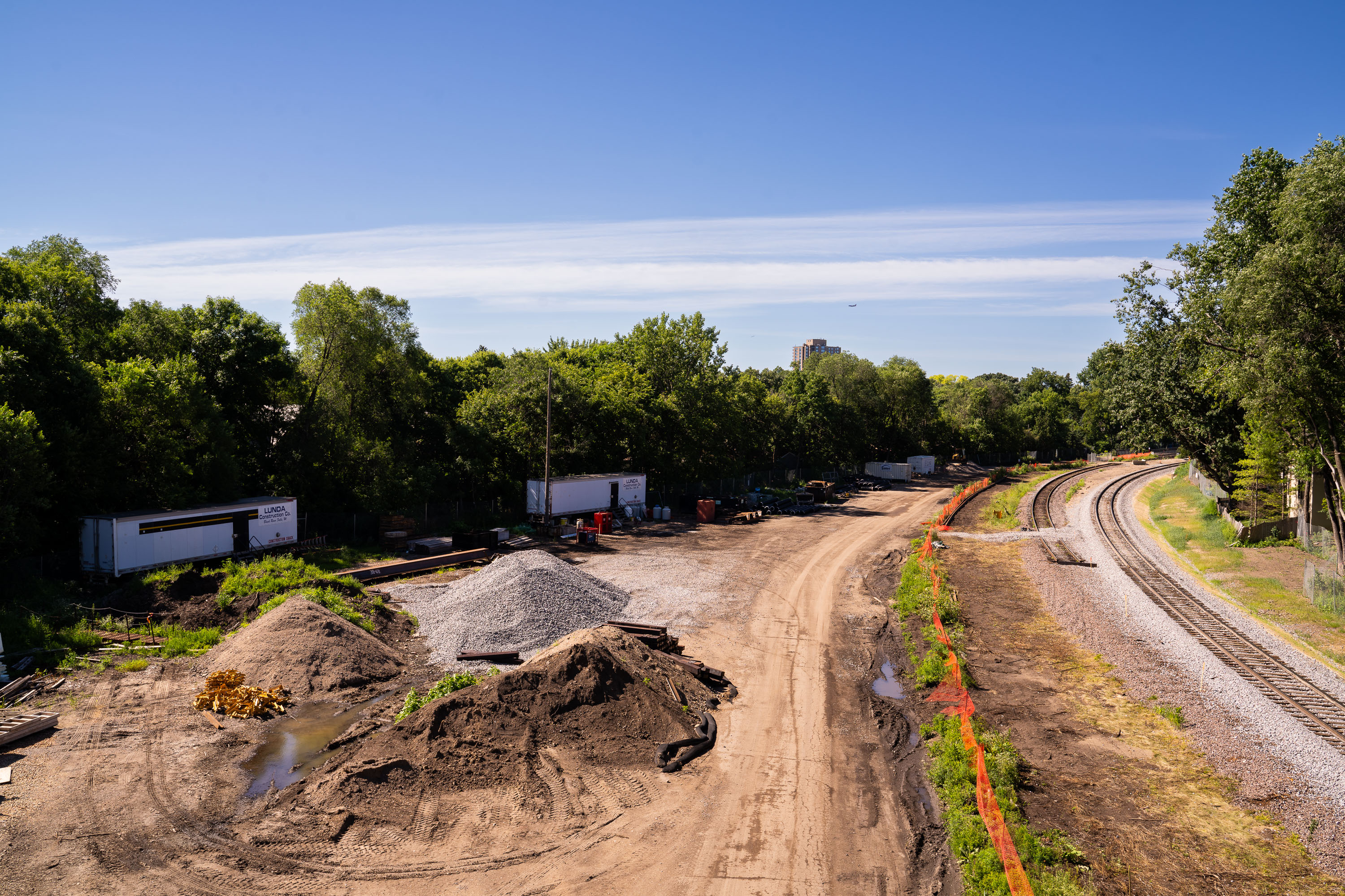 Southwest LRT construction site along Kenilworth Trail in Minneapolis with excavated earth and railroad tracks.