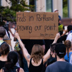 A woman holds up a sign that reads “Feds in Portland proving our point. Stay Strong PDX” outside the Federal Courthouse in downtown Minneapolis. Protesters gathered on July 23rd, 2020 to protest federal officers being deployed to cities around the country.