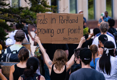 A woman holds up a sign that reads “Feds in Portland proving our point. Stay Strong PDX” outside the Federal Courthouse in downtown Minneapolis. Protesters gathered on July 23rd, 2020 to protest federal officers being deployed to cities around the country.